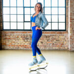 Woman posing indoors while wearing blue and yellow Fit Boots Rebound Boots.